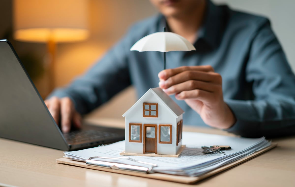 Model home protected by an umbrella over loan documents and keys